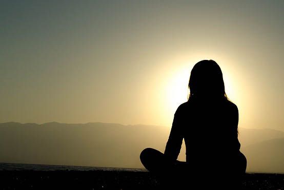 Женщина медитирует на закате
